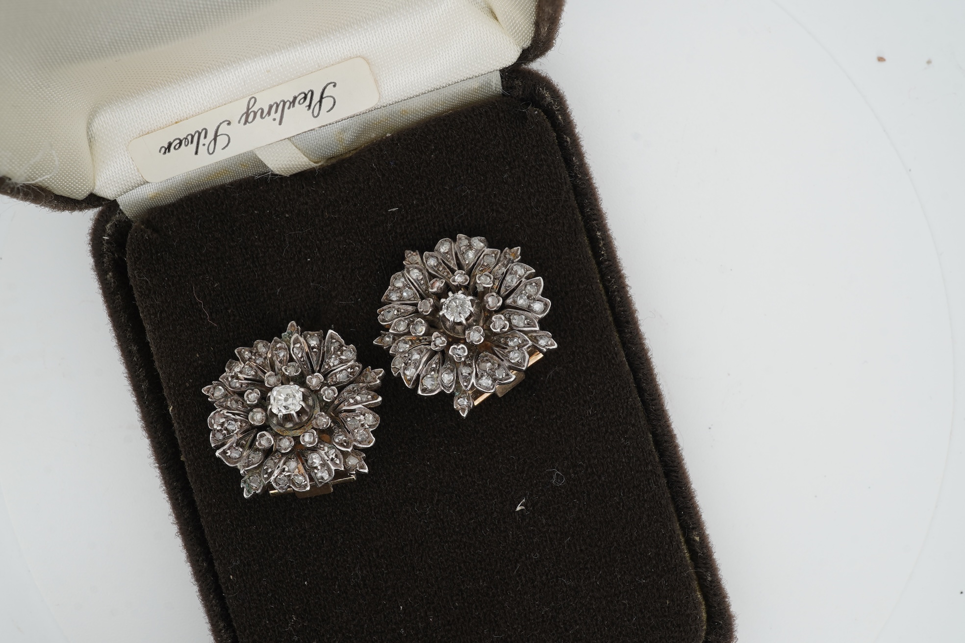 A pair of diamond ear clips 19th century and later, each designed as a wild rose, set with cushion-shaped and rose-cut diamonds, mounted in silver and gold, length 2.2cm each, later clip fittings